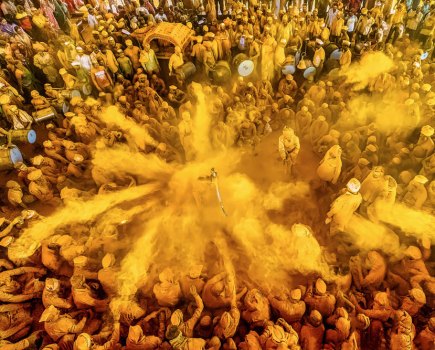 photo in the street of yellow powder being thrown at holi festival