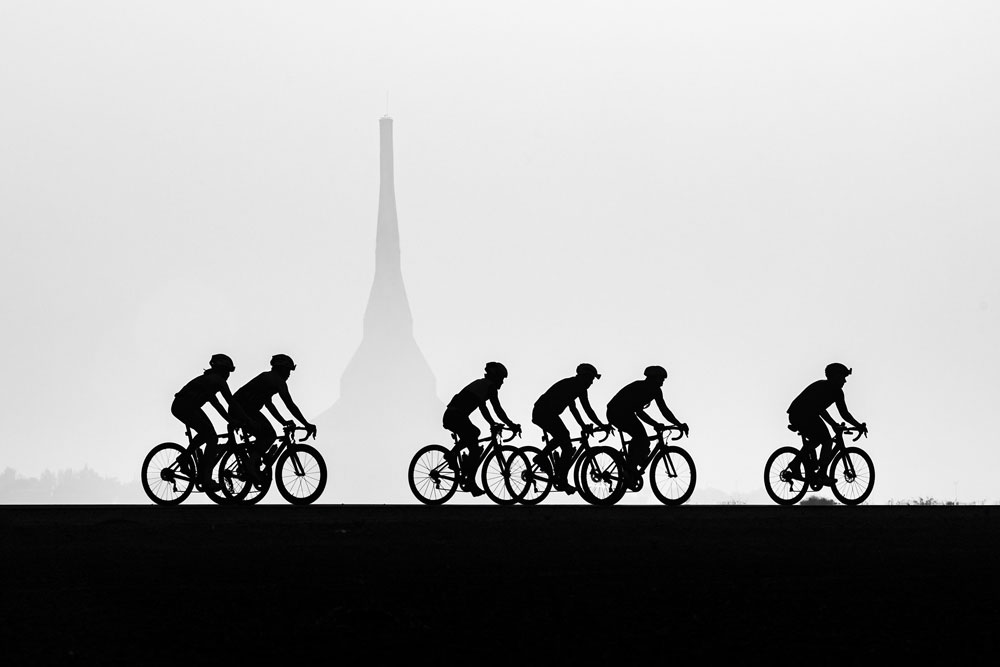 a group of cyclists with the eiffel tower shaped building in the background