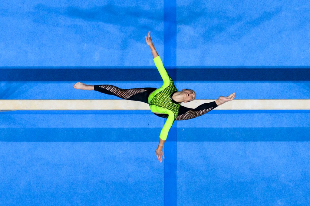 overhead shot on gymnast split on beam