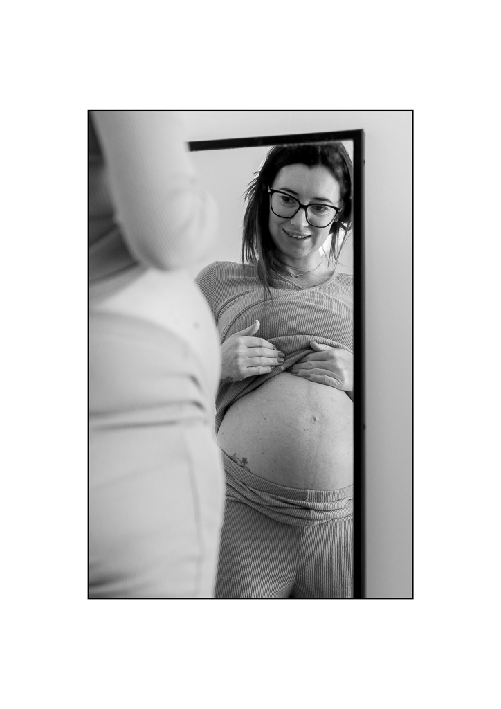 pregnant woman looking at her bump in the mirror