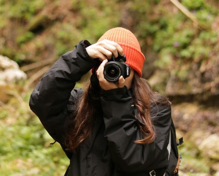 woman in an orange beanie taking a photo with a camera