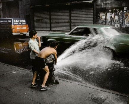 two boys playing with water by a water hydrant