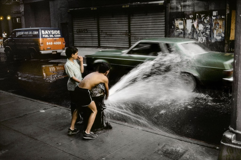 two boys playing with water by a water hydrant