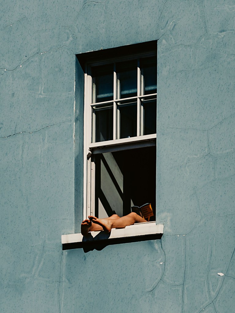 Colour photograph of a window with a person's feet sticking out of it