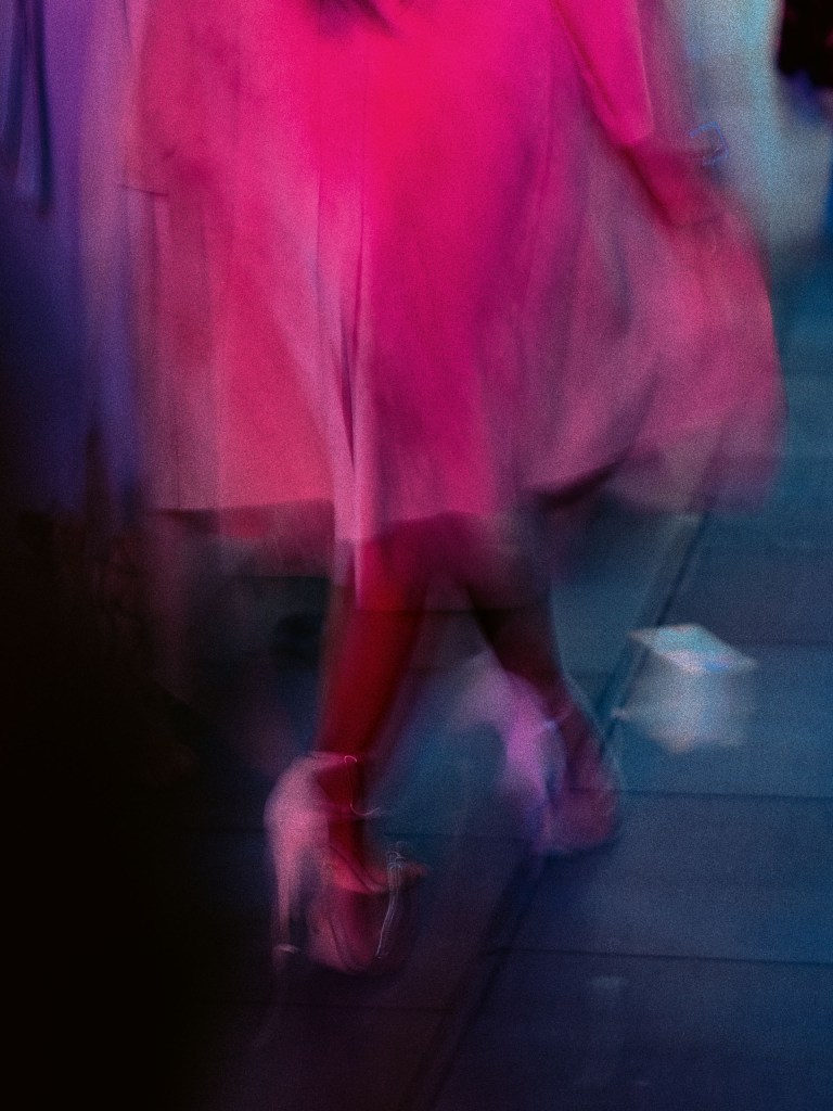a person wearing a pink skirt and pink shoes, blurred intentionally