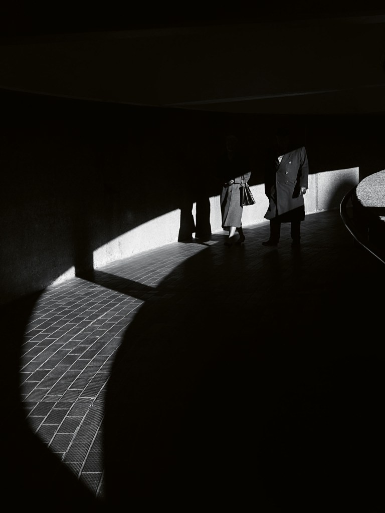 A black and white street scene including high-contrast shadows