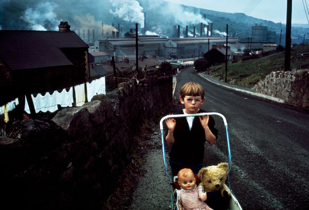 A young child pushing a pram up a hill