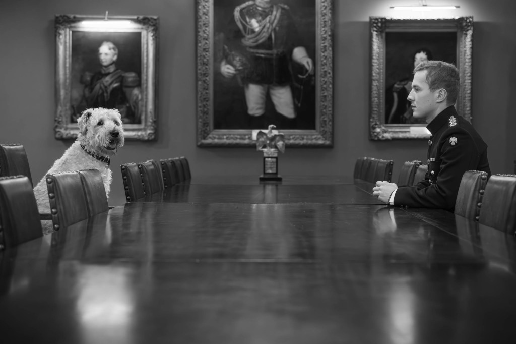 black and white photo of a man sitting across the table from a dog