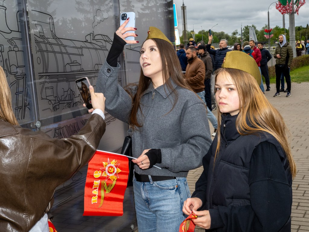 BREST, BELARUS - MAY 9, 2026: Teenagers take a selfie wearing the piltotka, a traditional foldable military side cap associated with the Soviet Union. I became a standard Red Army uniform cap in December 1935 and was worn by both soldiers and officers throughout World War II. Image Credit: Peter Dench
