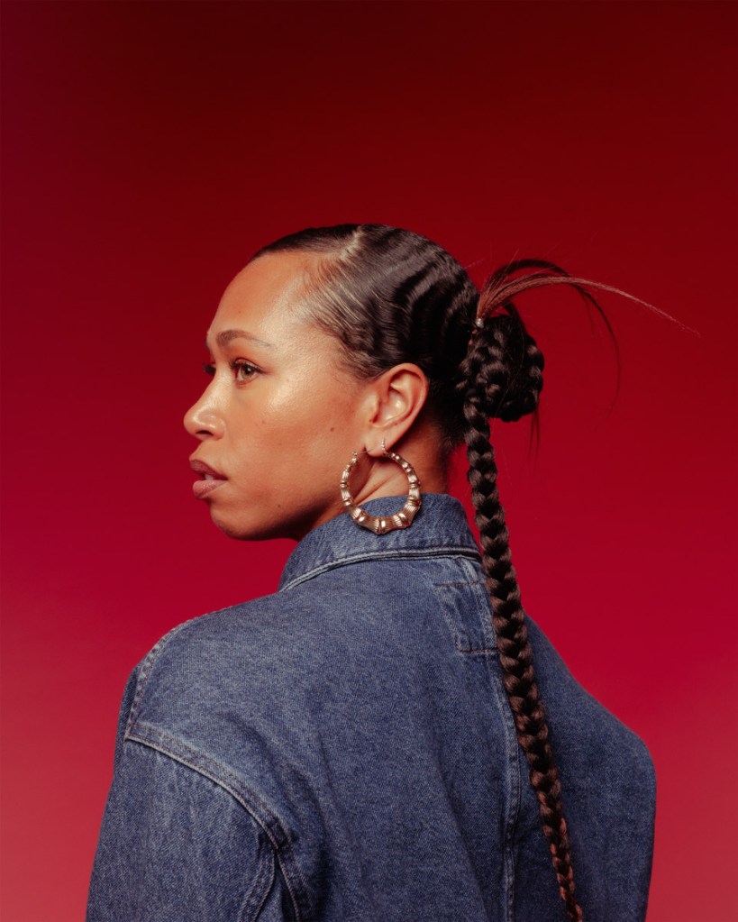 portrait of a woman in a denim jacket looking to the side with red background