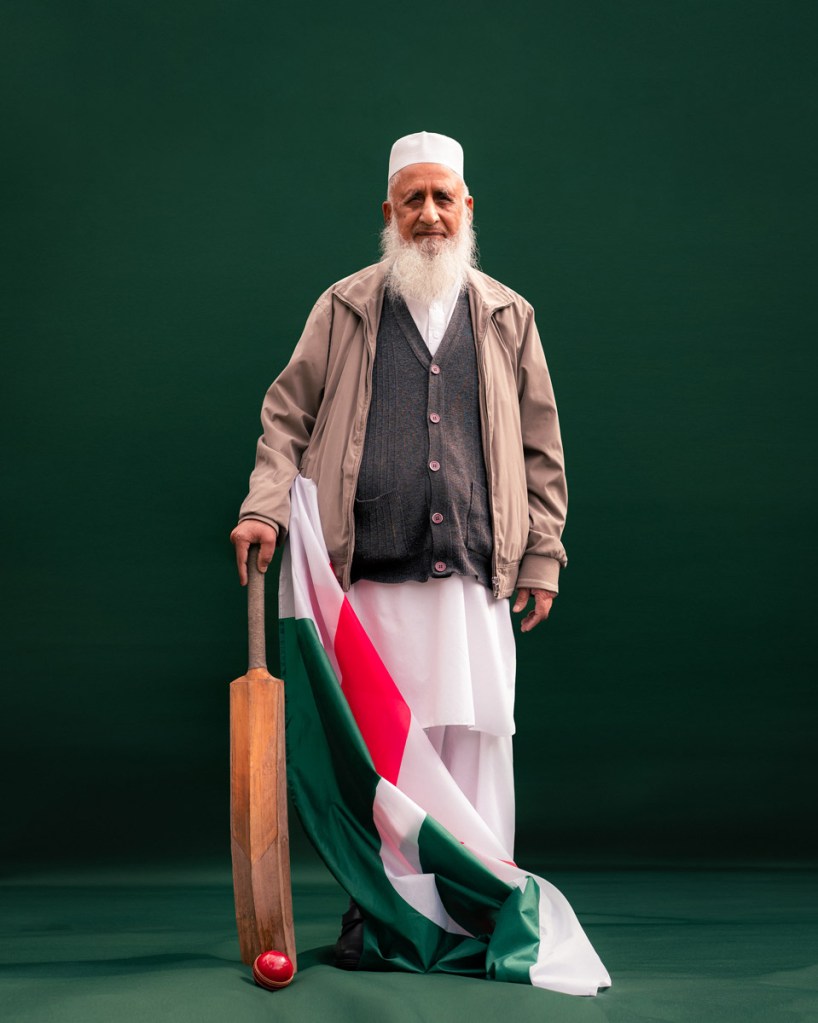 man stood with cricket bat, st georges flag and pakistan flag