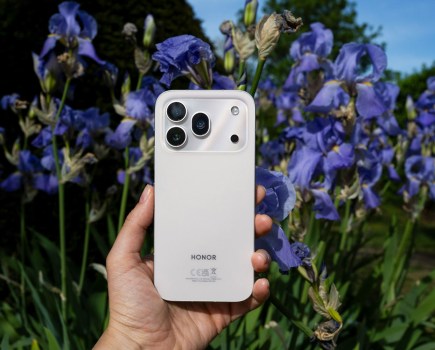 Honor 600 Pro in hand, purple flowers
