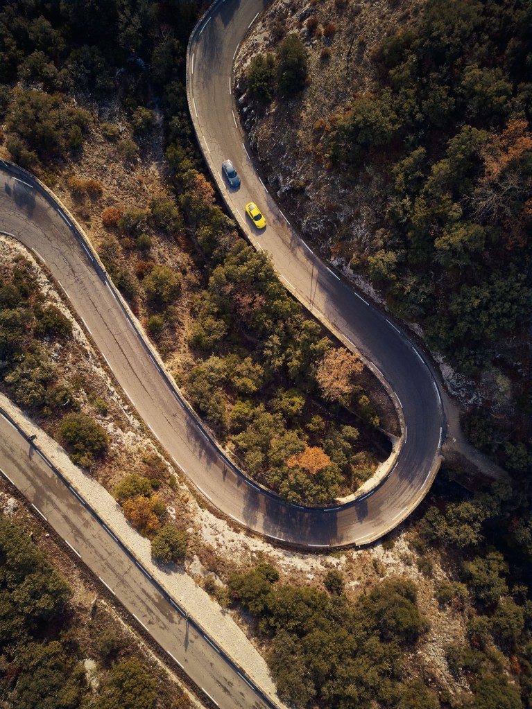 aerial shot of a car going around a curved road