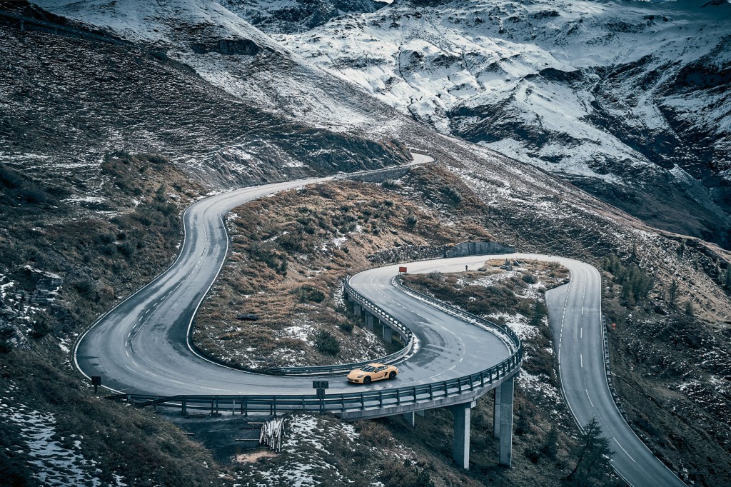 aerial shot of a car going around a curved road