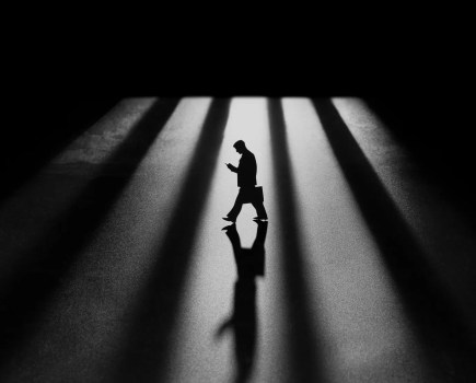 silhouette of a man walking inbetween rays of light