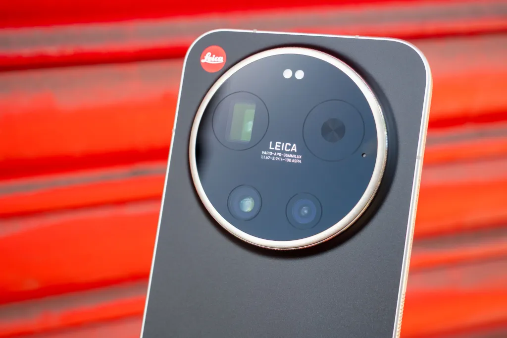 A close-up of the lens units of the Leica Leitzphone in front of some bright red shutters