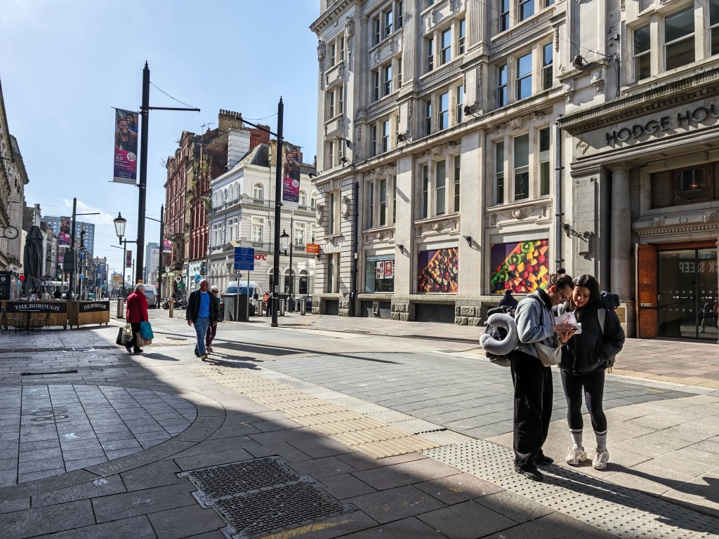 Two people stand in a street looking at a phone