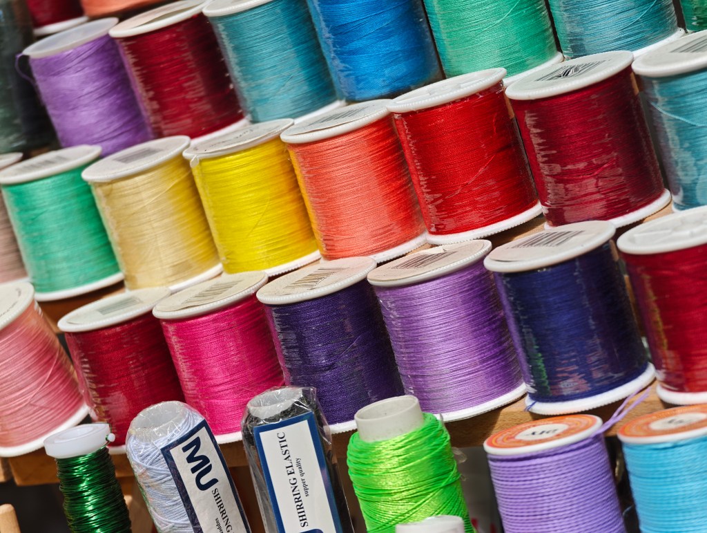 Brightly coloured cotton spools all lined up