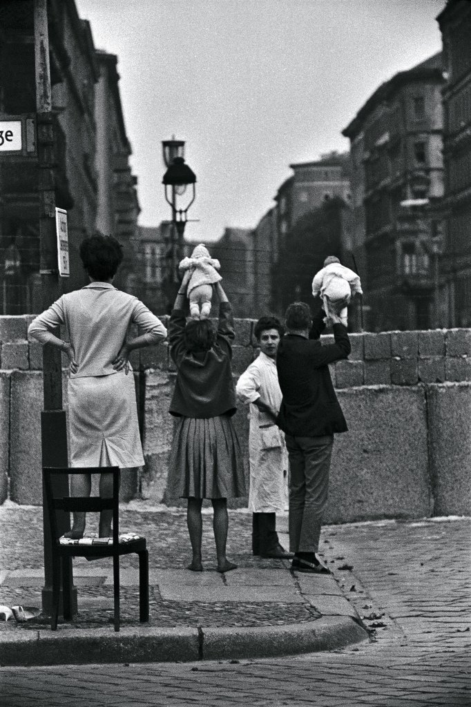 A 1961 photo of West Berlin parents holding up their babies over the concrete wall for grandparents in East Berlin to see.