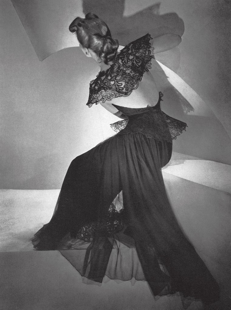 Black and white image, woman wearing a long black dress sits with her back to the camera