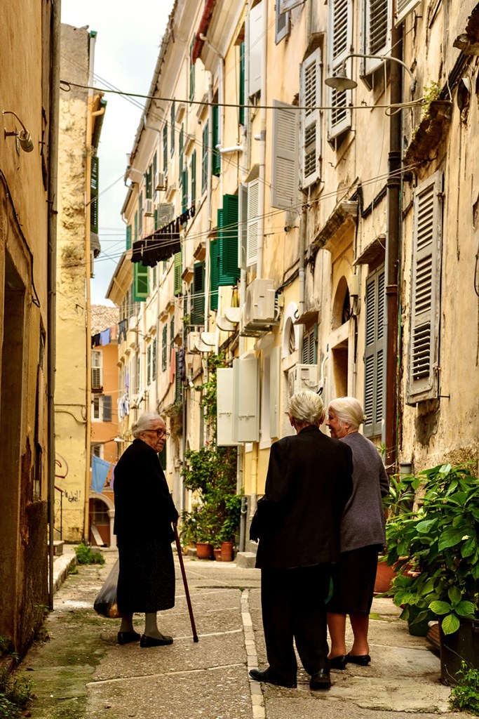 three elderly women talking on a street in old corfu town