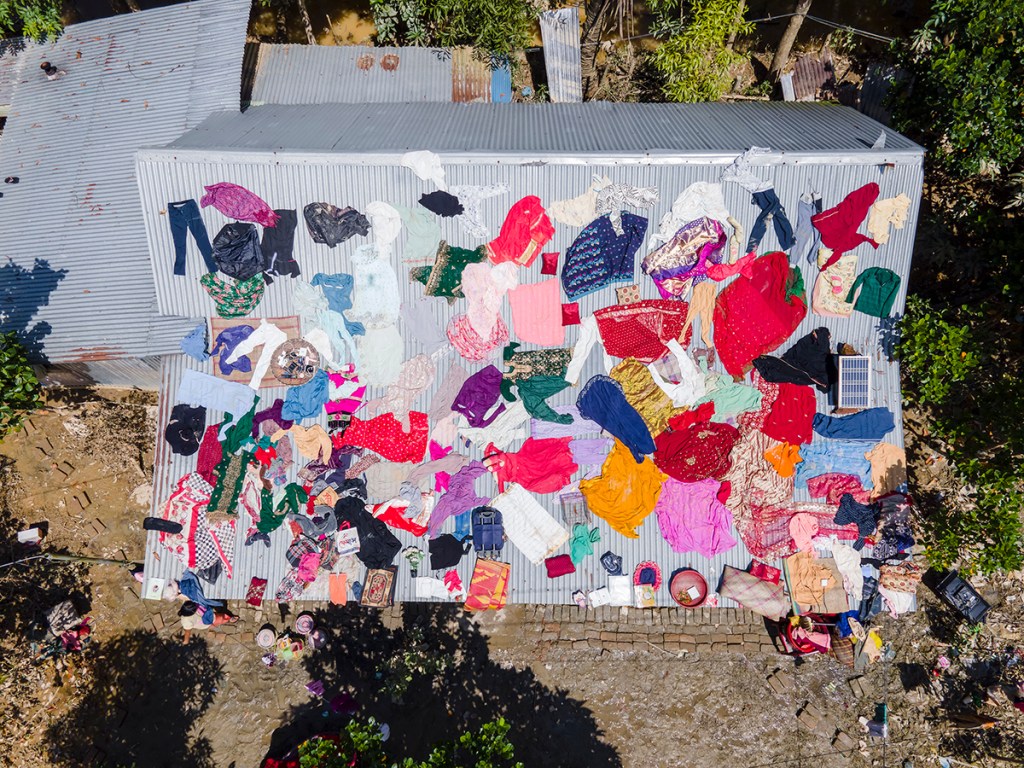 Flood-affected residents dry clothes and household belongings on the roof of a house in Chhagalnaiya upazila, Feni district,