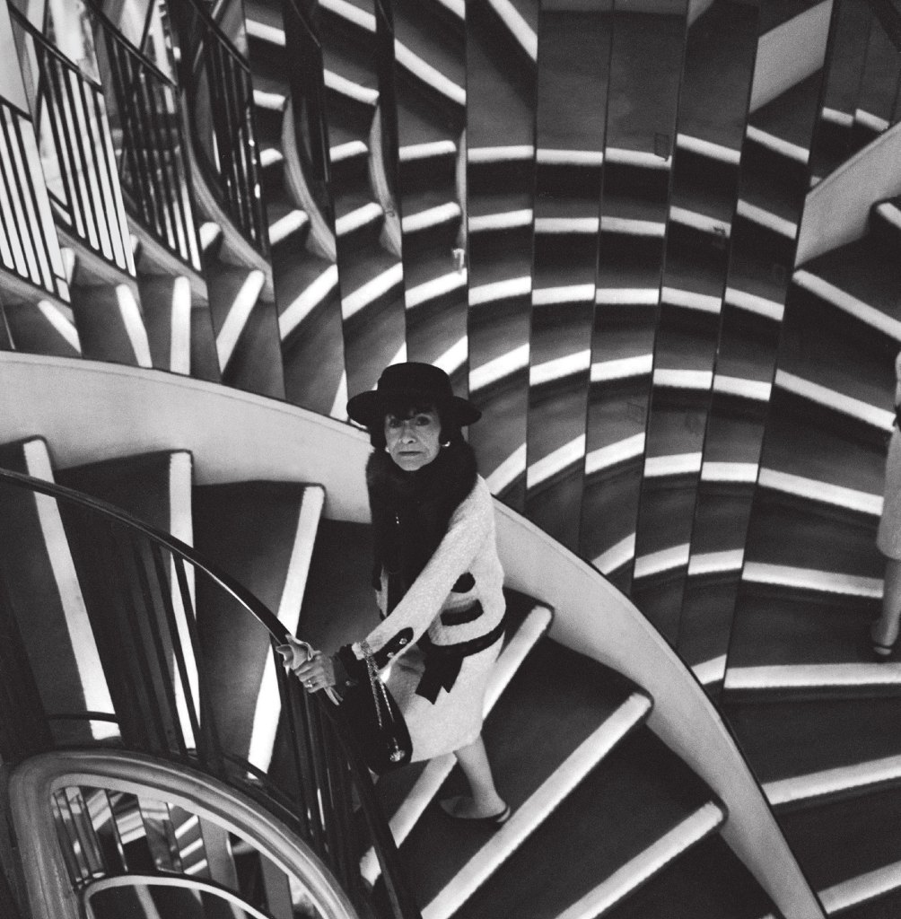 Gabrielle Chanel photographed on the mirrored staircase at 31 rue Cambon by Cecil Beaton in 1965. Cecil Beaton. Vogue ©Conde Nast