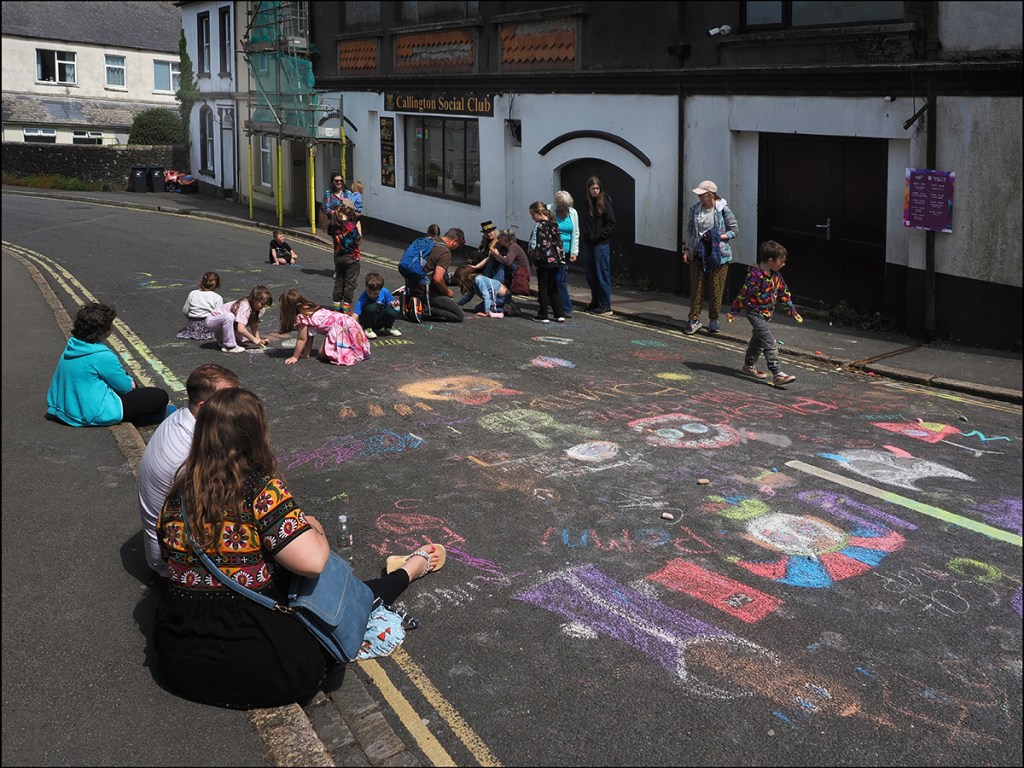 photo of children making chalk paintings on a road