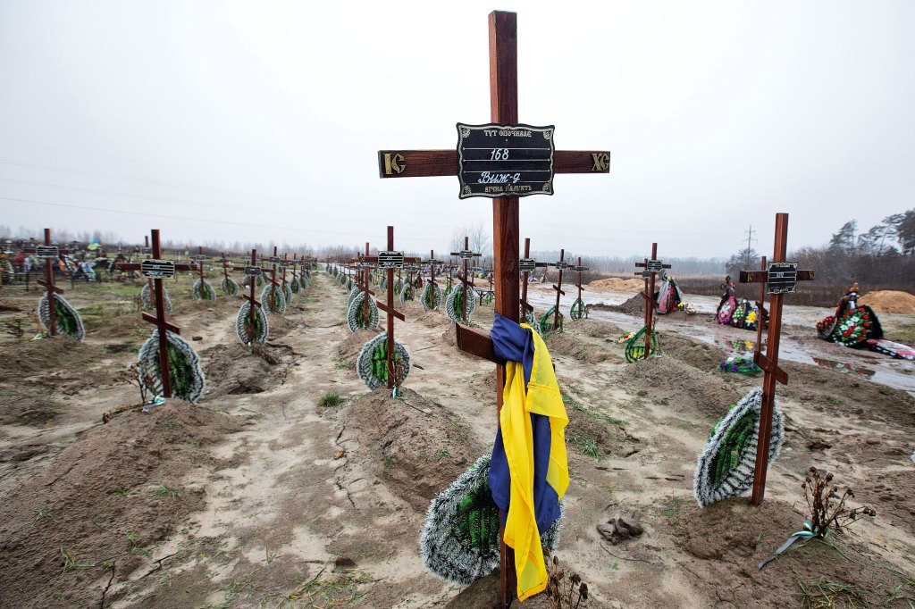Rows of wooden crosses with numbers marking nameless graves of war victims at a cemetery in Bucha, Ukraine.