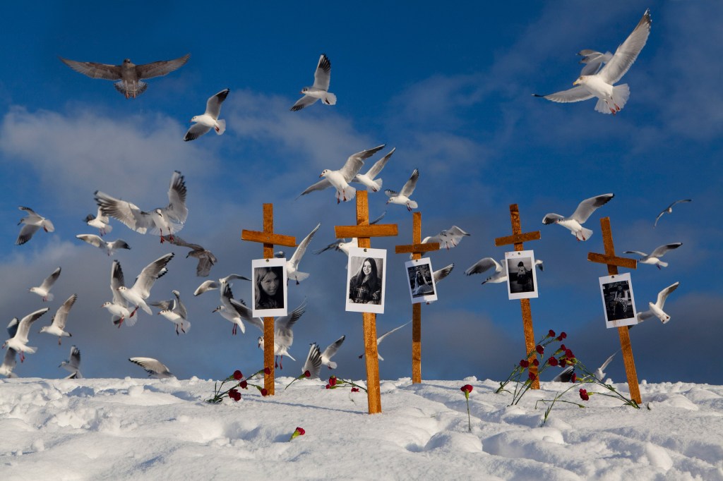 birds flying over four gravesite crosses
