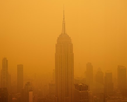 A thick, apocalyptic orange smoky haze from Canadian wildfires completely obscuring the skyline and Empire State Building in New York.