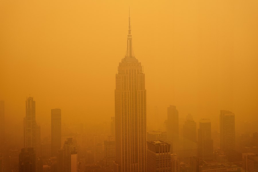 A thick, apocalyptic orange smoky haze from Canadian wildfires completely obscuring the skyline and Empire State Building in New York.