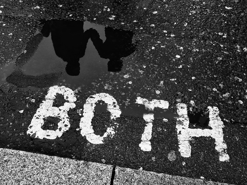 photo of the word both on the floor next to a puddle with a reflection of two people
