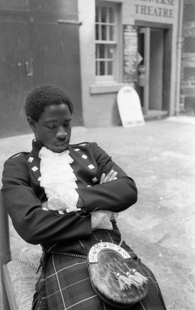 a man dressed in a kilt sleeping on a chair