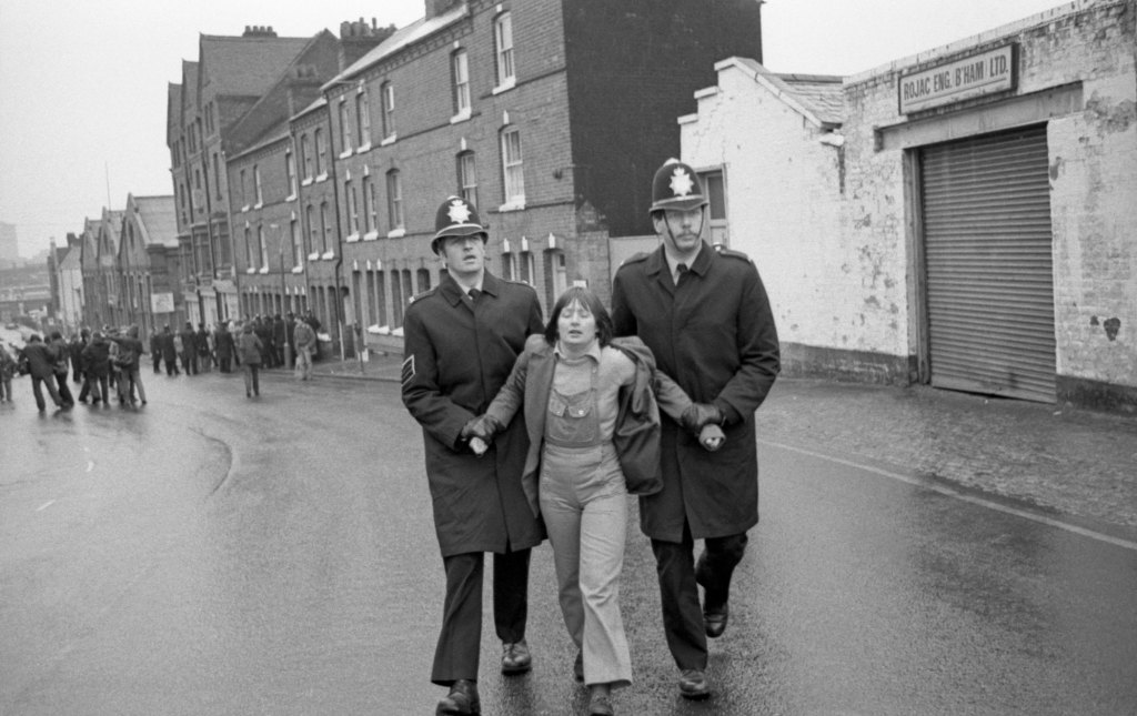 black and white image of two policeman arresting a woman