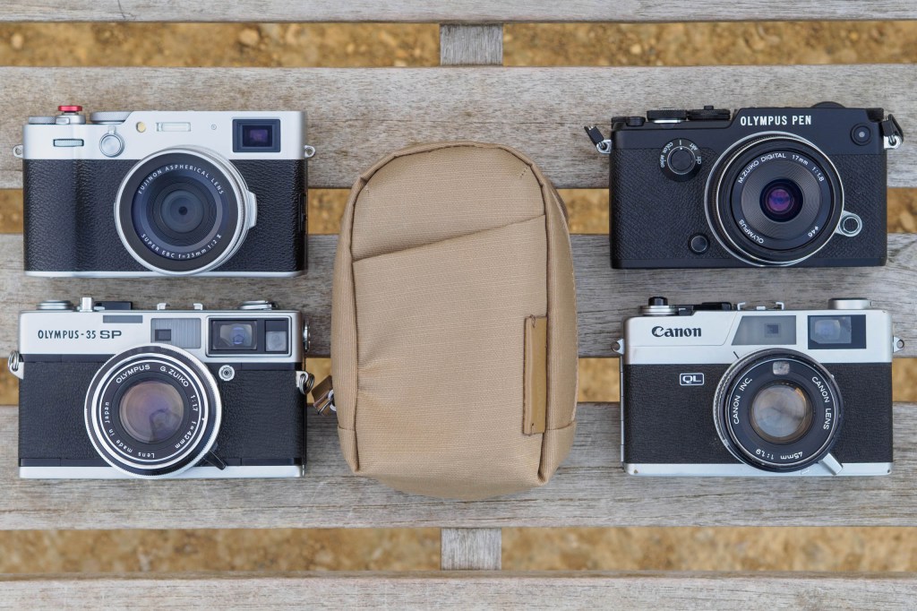 Vanguard VEO Metro Medium Compact Camera Bag in Beige, with a selection of cameras that will fit inside