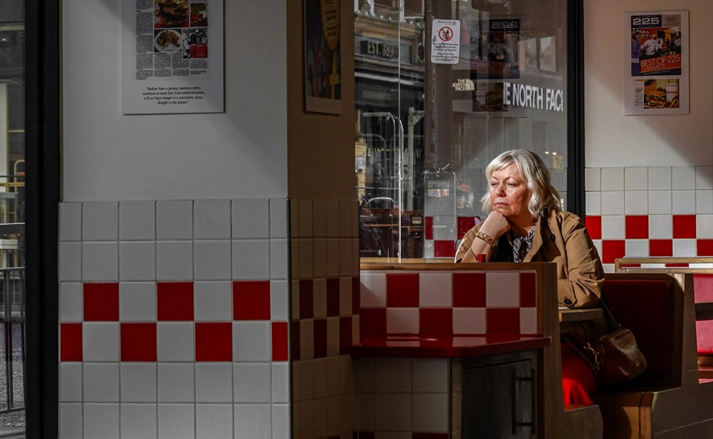 Photo of a woman in a diner looking out the window