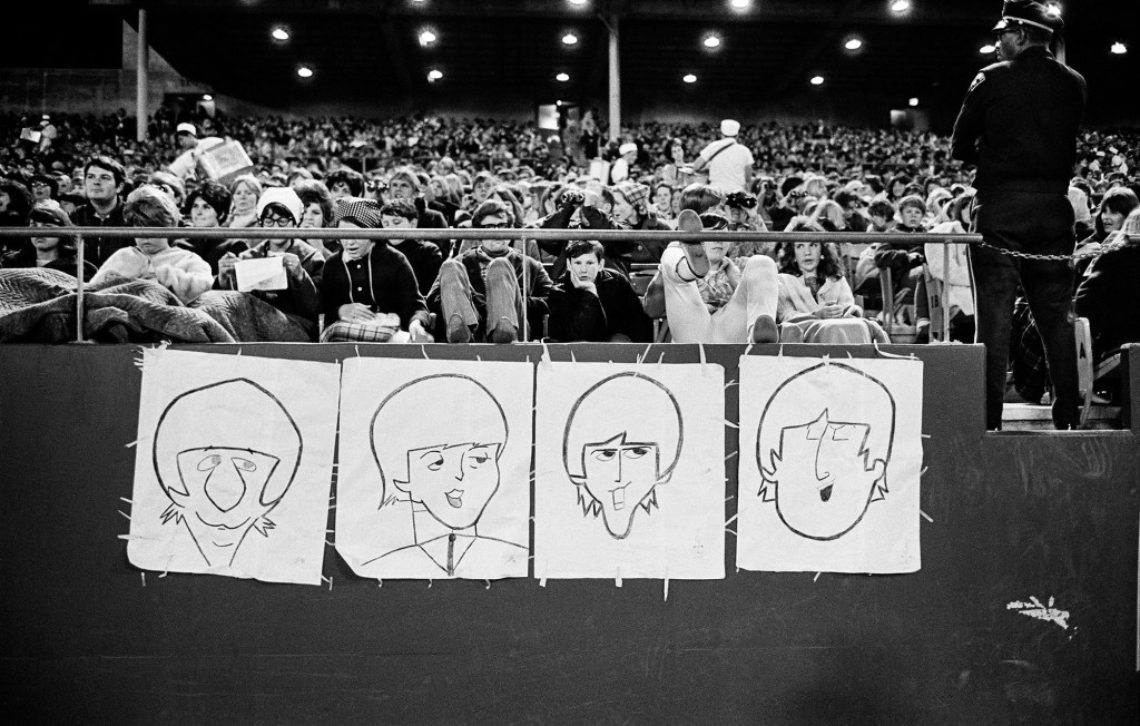 Fans in the stadium stands display caricatures of The
Beatles at Candlestick Park. Image Credit: 2026 © Jim Marshall ONE TIME USE
