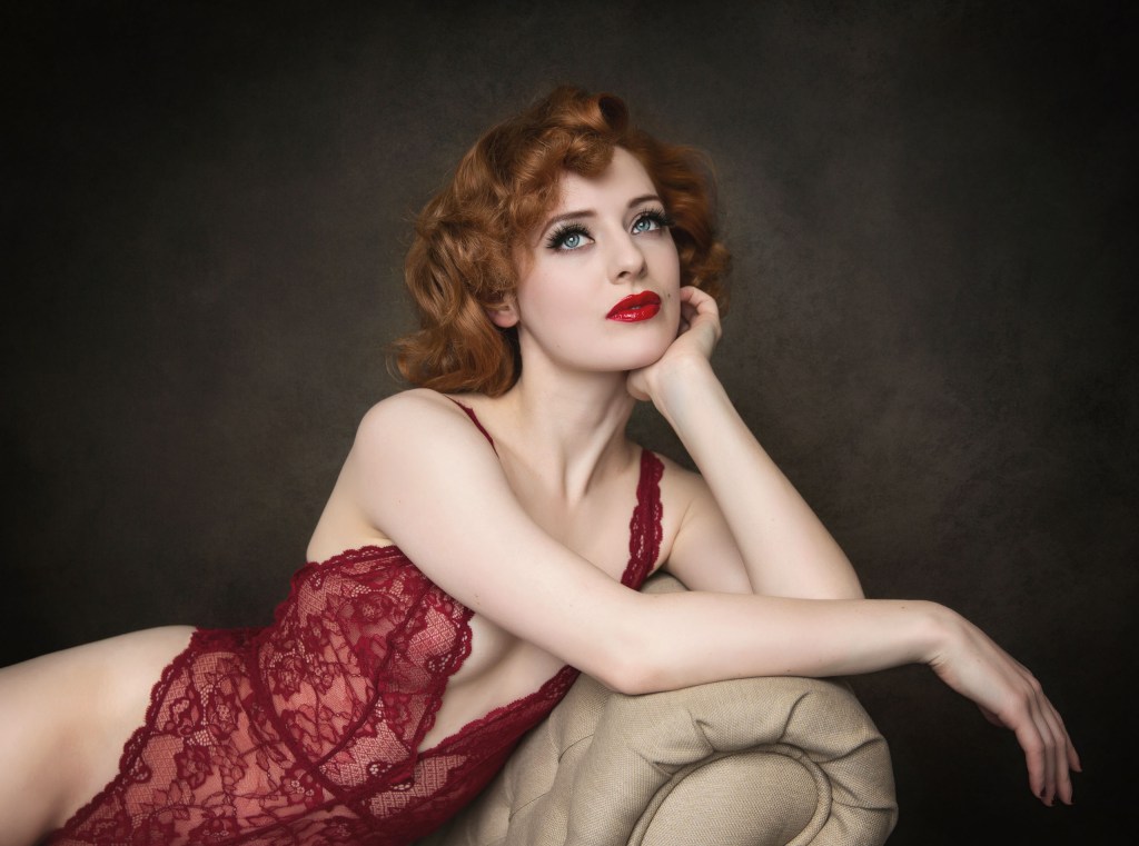 A woman with red hair posing on a chez longue