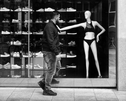 person walking past a shop with model in the window