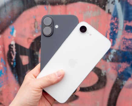 iPhone 17 and iPhone 17e in hand against a graffitied wall