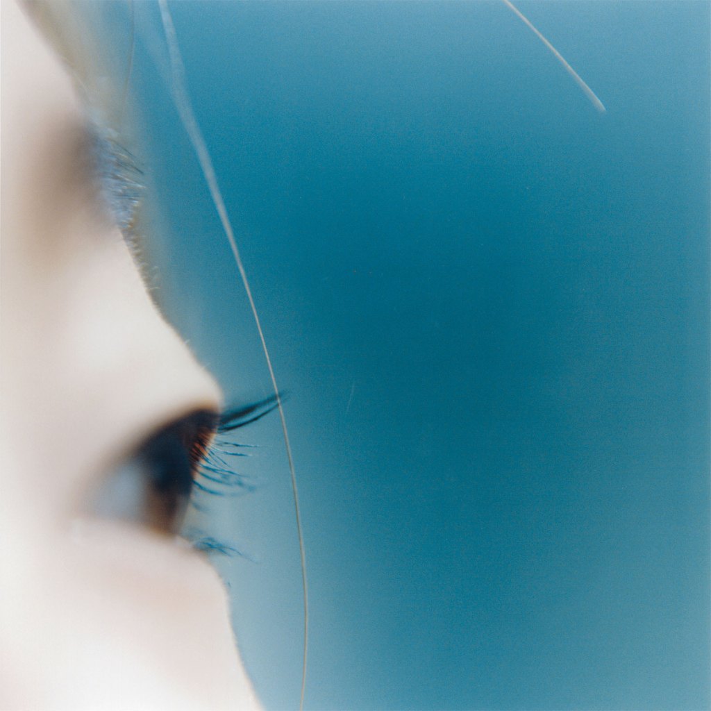 Close-up colour photograph of a person’s eye on a blue background.