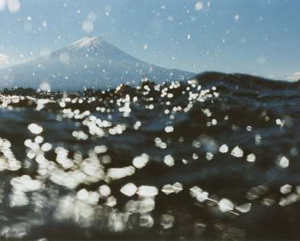 Colour photograph of Mount Fuji in the distance, taken from above the water.