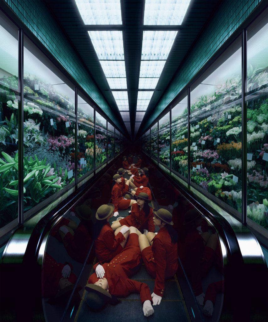 Colour photograph of several women wearing a red blazer-skirt uniform and brown hats sitting along a moving walkway.