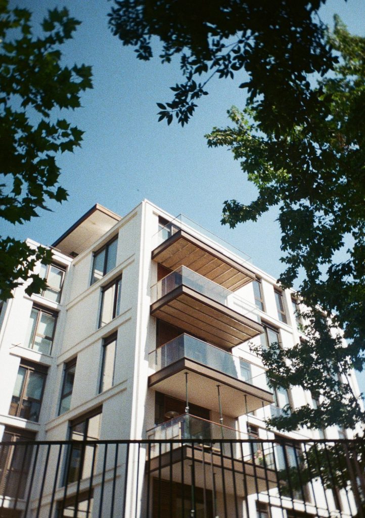 Sample photograph from the Lomography Half-frame Simple Use Camera, shot on Lomo Color Negative 400 film showing an apartment building with balconies behyind a fence