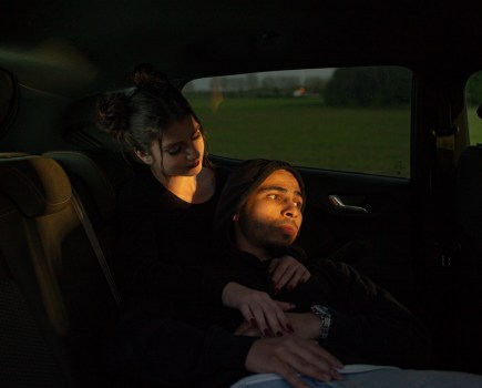 couple sat in a car with a small crack of golden light on their faces