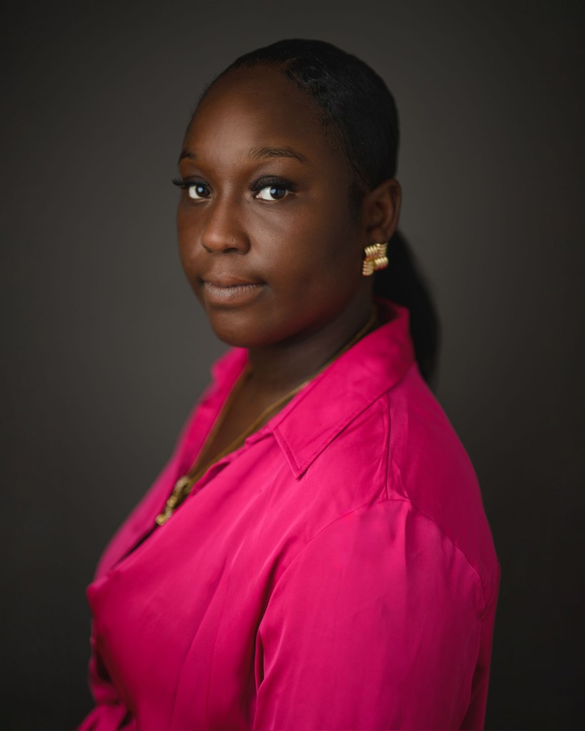 A portrait of a woman wearing a pink top