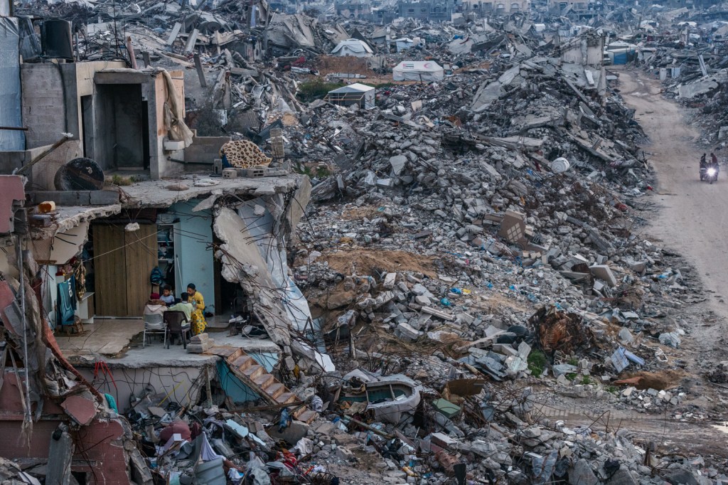 a family sat amongst rubble in gaza