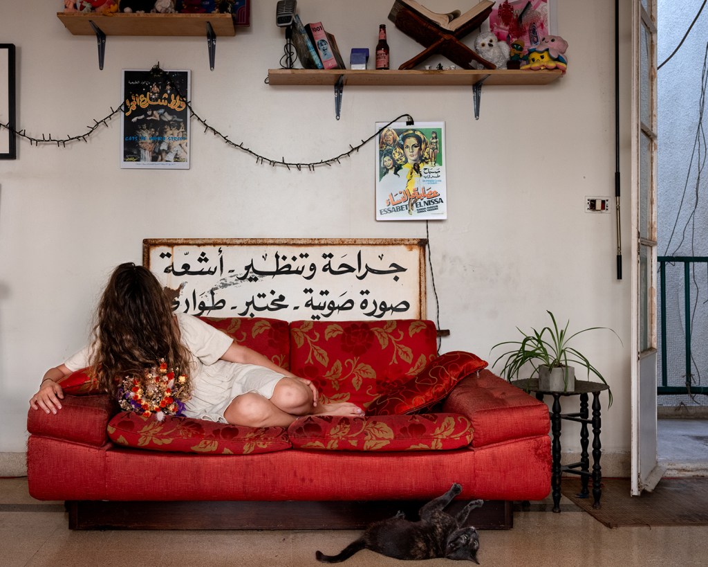 A woman laying on a red sofa, her face obscured by her hair