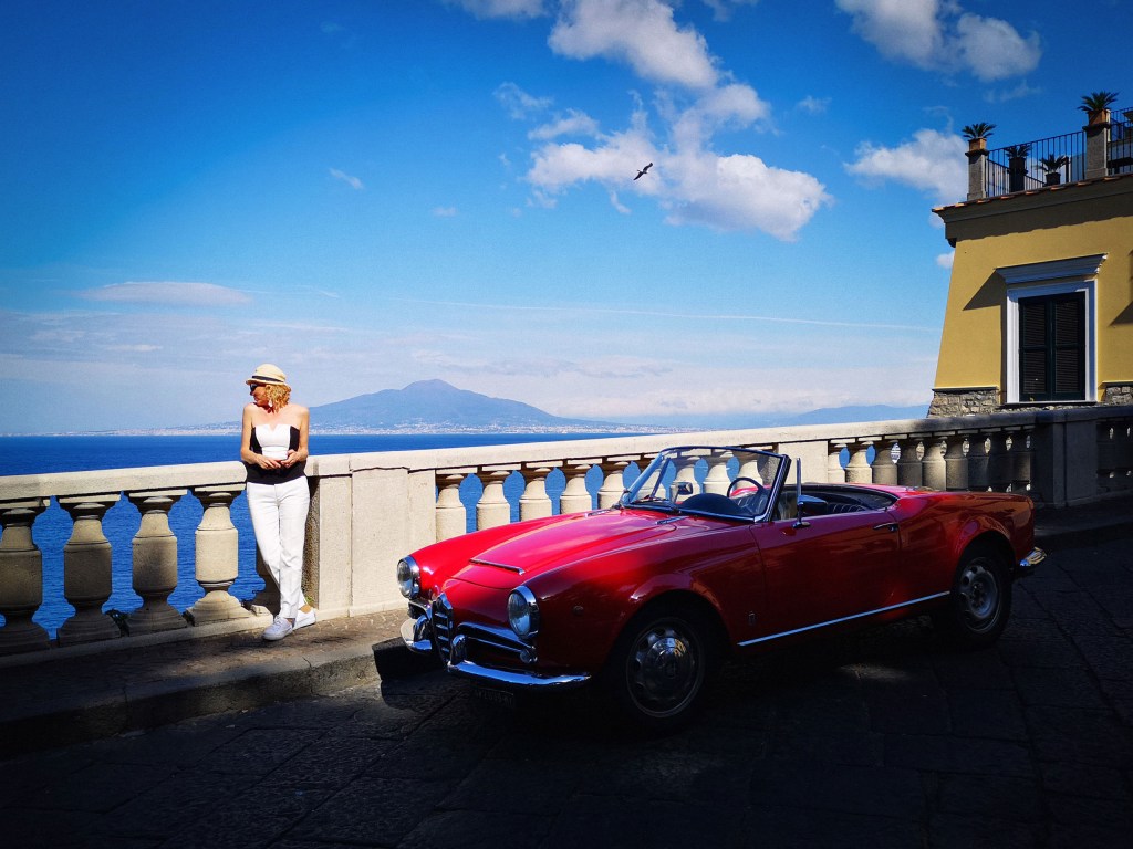 A person standing next to a red car